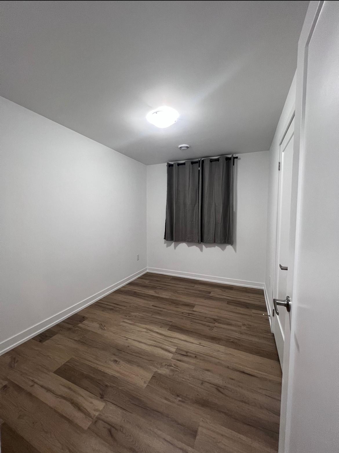Bedroom with wood-look flooring and a large curtained window